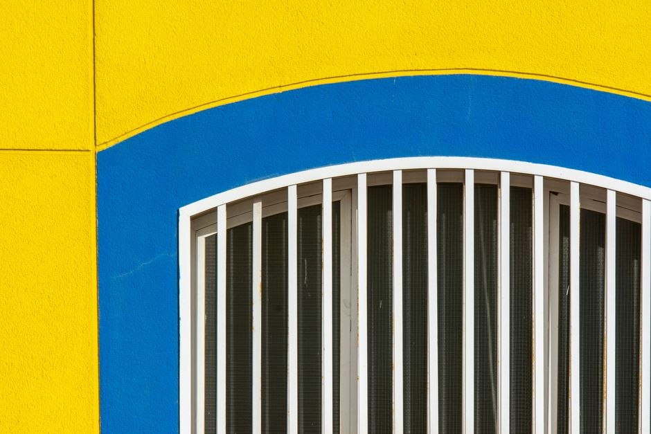 A vibrant facade with yellow and blue colors surrounding an arched window.
